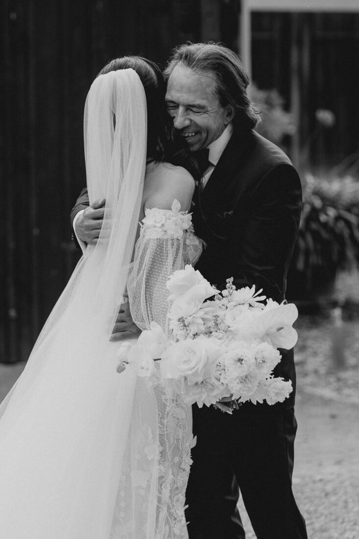 Emotionale Schwarz-Weiß-Aufnahme: Der Brautvater umarmt seine Tochter innig nach dem Frist Look Moment auf dem Steinbachhof.