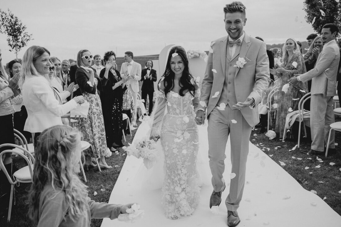 Brautpaar läuft lachend beim Auszug durch die Reihen der Gäste bei ihrer Hochzeit auf dem Steinbachhof.