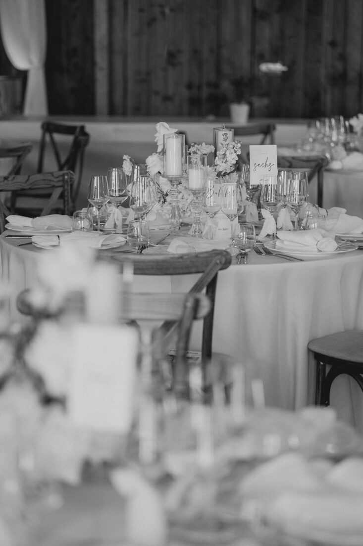 Festlich gedeckter runder Tisch in der rustikalen Scheune des Steinbachhofs in Schwarz-Weiß.