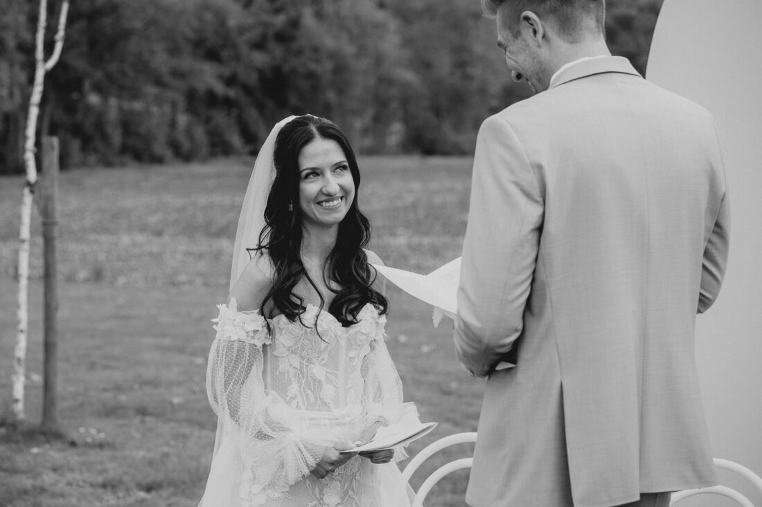 Glückliche Braut schaut ihren Bräutigam während der Zeremonie auf dem Weingut Steinbachhof an.