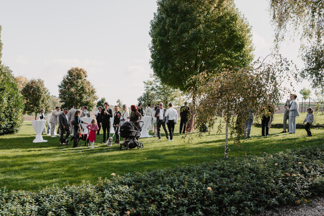 Hochzeitsgäste stehen beim Sektempfang im Garten des Steinbachhofes.