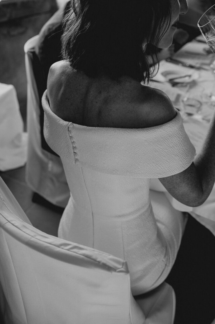 Detailaufnahme der Knopfleiste eines eleganten, schulterfreien Brautkleides von hinten fotografiert.