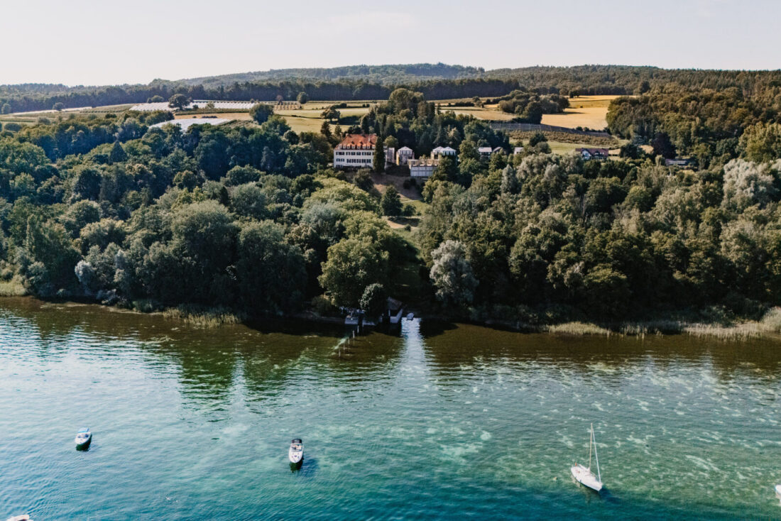 Luftaufnahme von Schloss Marbach auf der Halbinsel Höri, umgeben von Wald und dem Bodensee.