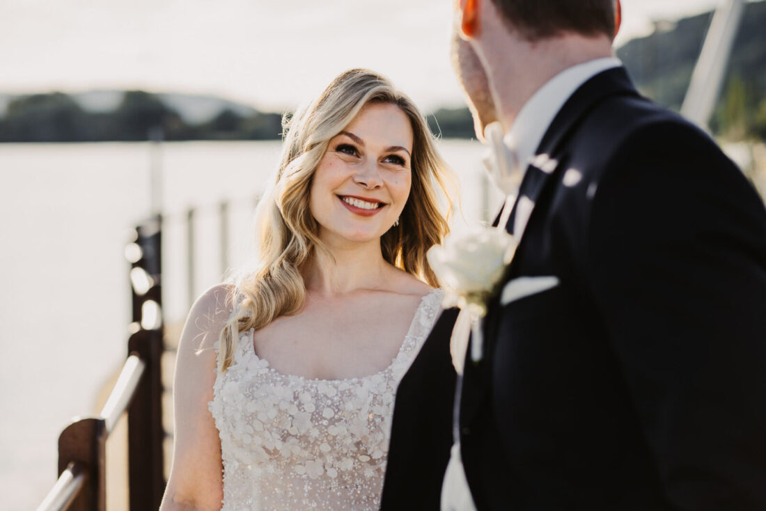 Braut schaut ihren Bräutigam während eines Portraits am Wasser in Ludwigshafen an