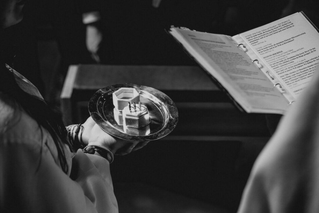 Die Eheringe auf einem Tablett werden dem Pfarrer bei der kirchlichen Trauung gereicht.