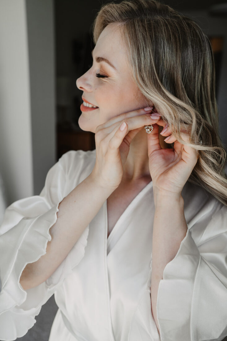 Close-Up von der Braut wie sie sich beim Getting Ready die Ohrringe ansteckt.