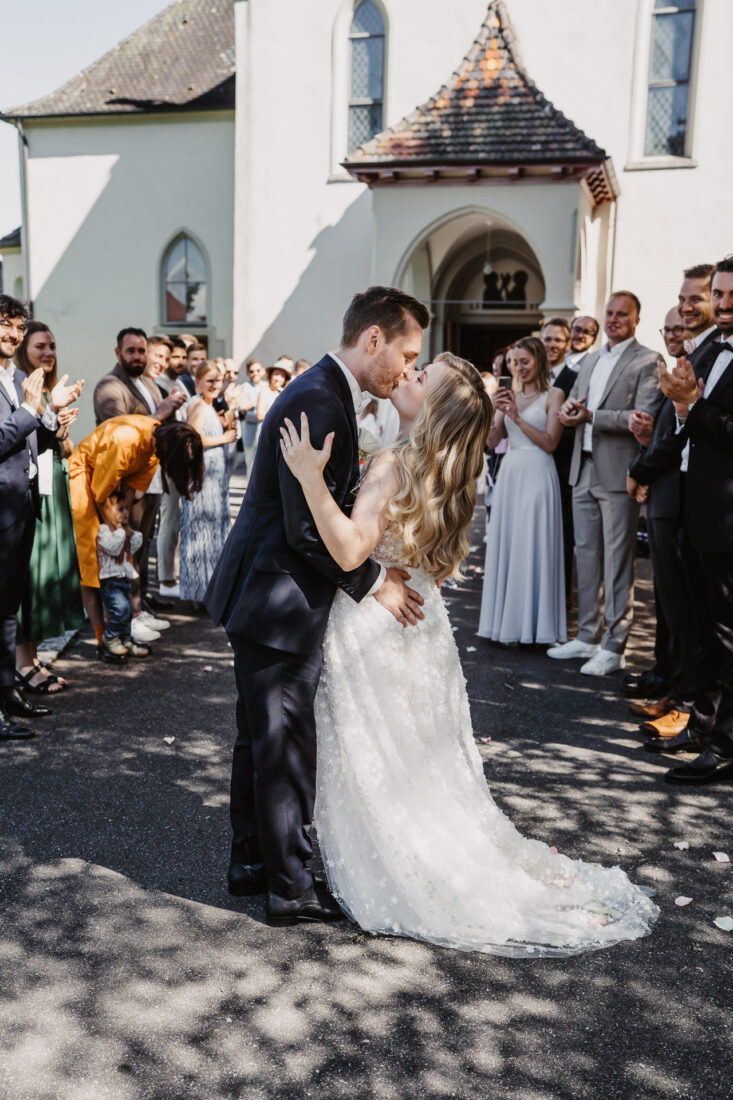 Brautpaar küsst sich vor der Kirche in Bodman-Ludwigshafen während die Gäste im Spalier applaudieren
