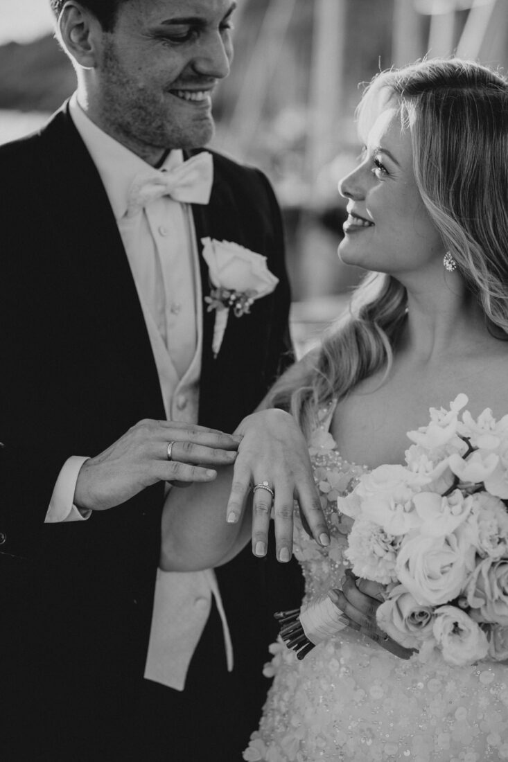 Stilvolle schwarzweiß Aufnahme einer Brautpaares, das glücklich ihre Eheringe in die Kamera hält