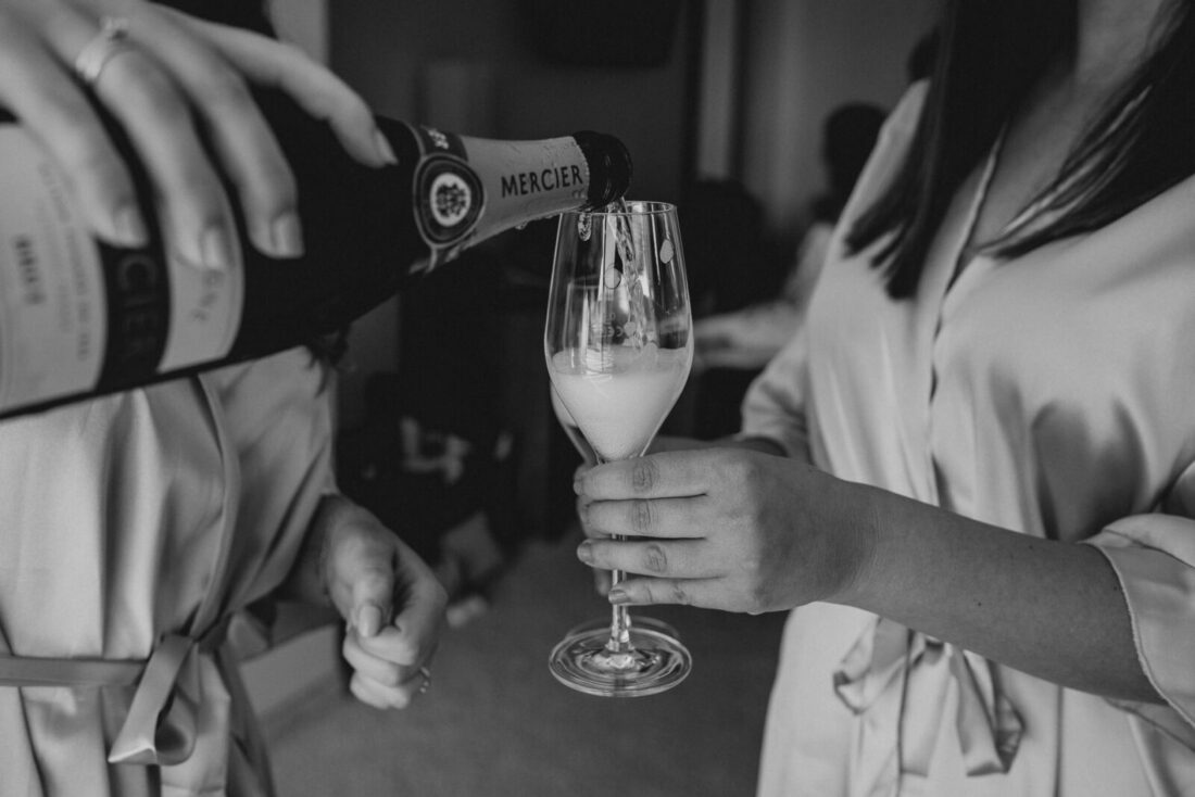 Die zwei Bridemaids schenken beim Getting Ready Champagner in ein Sektglas.