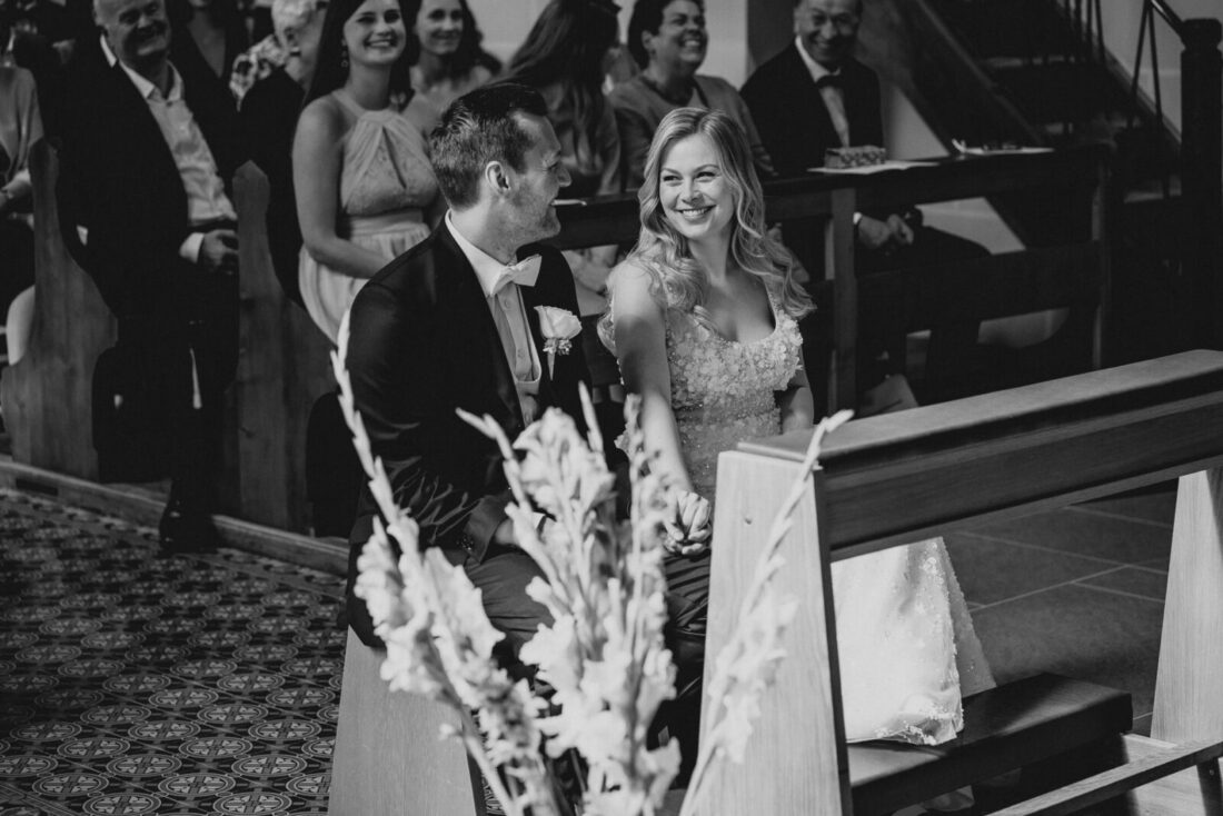 Braut und Bräutigam lächeln sich während der kirchlichen Trauung in Bodman-Ludwigshafen verliebt an.