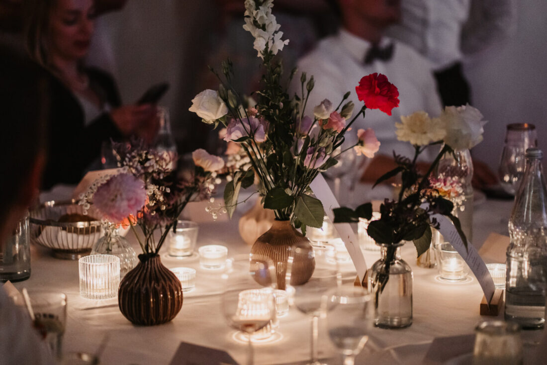 Blumen und Kerzen auf einem Hochzeitstisch während der Abendfeier
